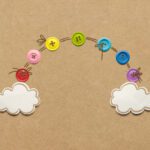 Creative concept photo of a rainbow and clouds made of paper on brown background.